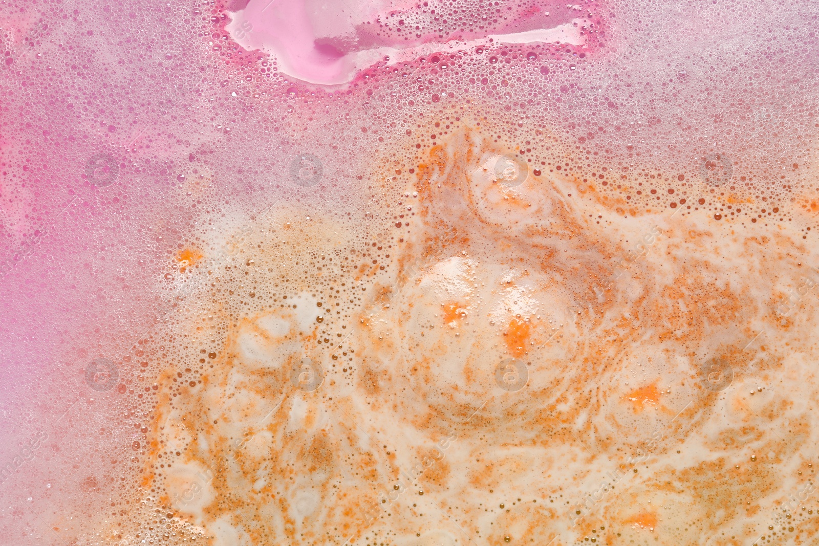 Photo of Colorful foam after dissolving bath bomb in water, closeup