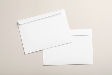 White paper envelopes on beige background, flat lay