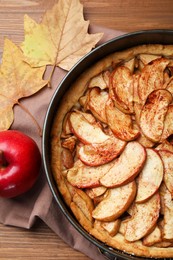 Photo of Delicious apple pie, fresh fruit and dry leaves on wooden table, flat lay