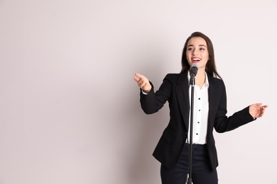 Photo of Young businesswoman with microphone on color background. Space for text