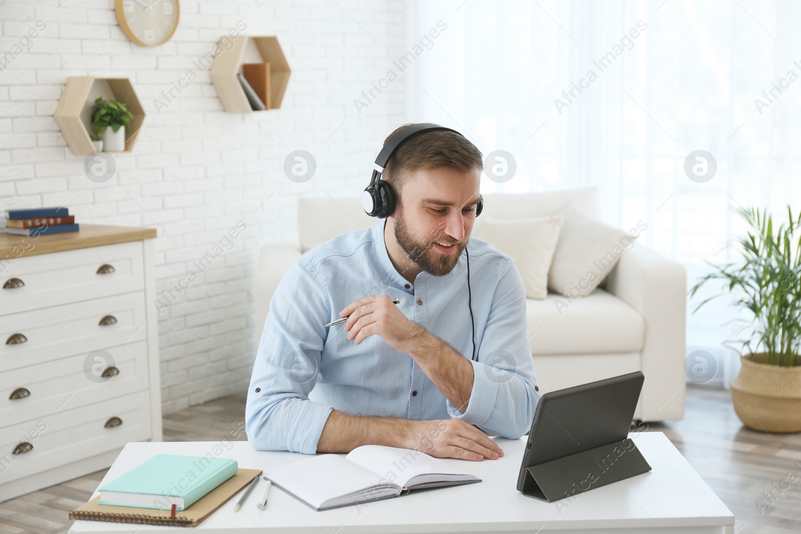 Photo of Young man watching online webinar at table indoors