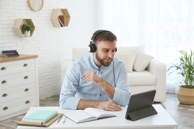 Young man watching online webinar at table indoors