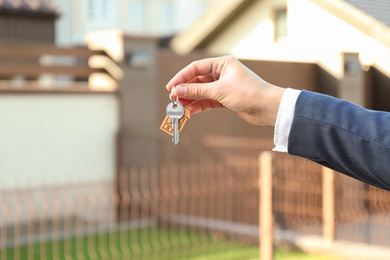 Photo of Real estate agent holding key outdoors, closeup