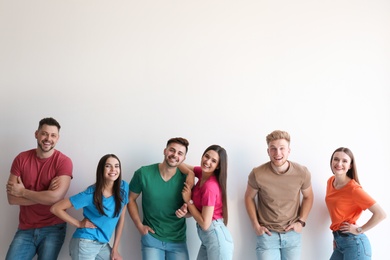 Group of happy people posing near light wall