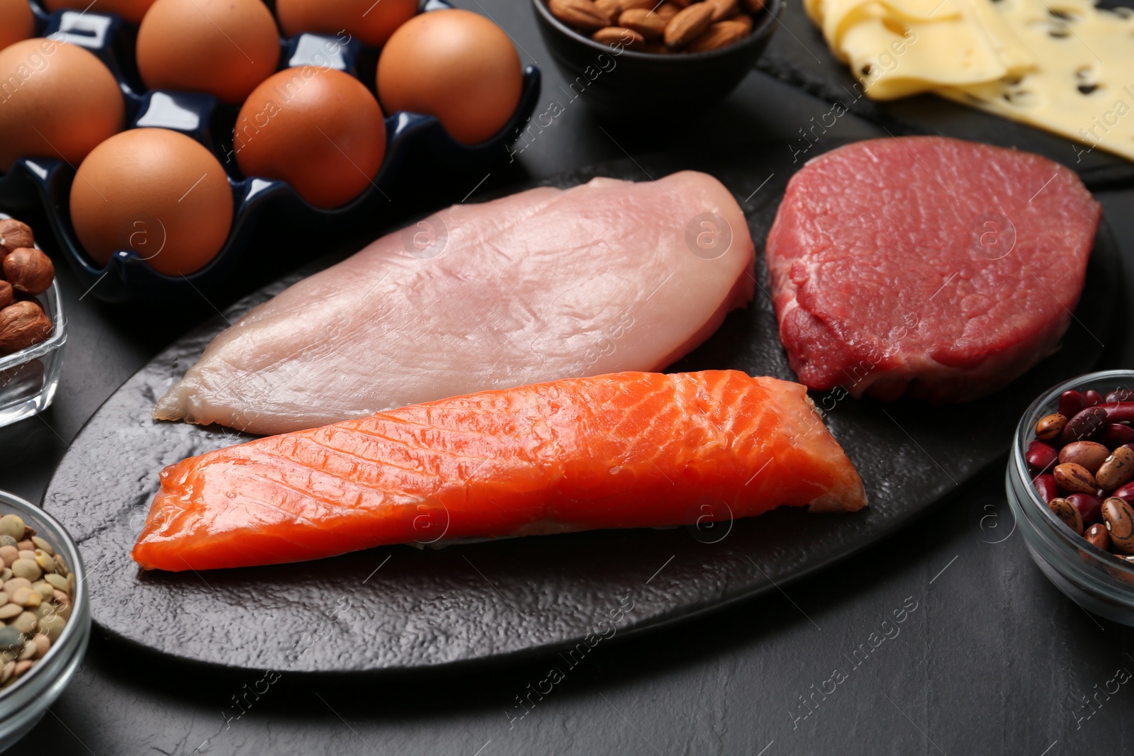 Photo of Fresh meat and other products on black table. Sources of essential amino acids