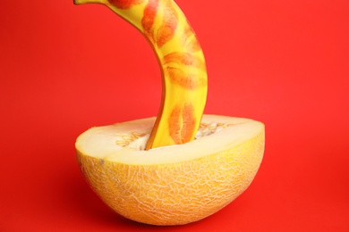 Photo of Fresh banana with lipstick marks and melon on red background. Sex concept