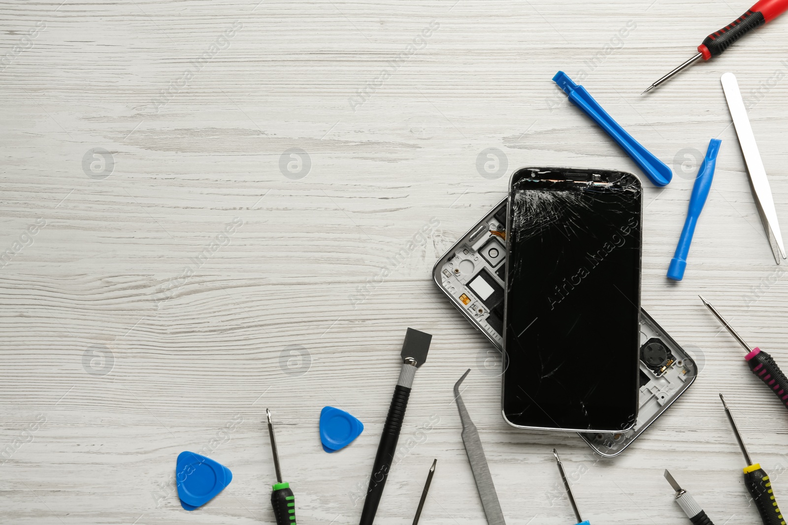 Photo of Damaged smartphone and repair tools on wooden background, flat lay. Space for text