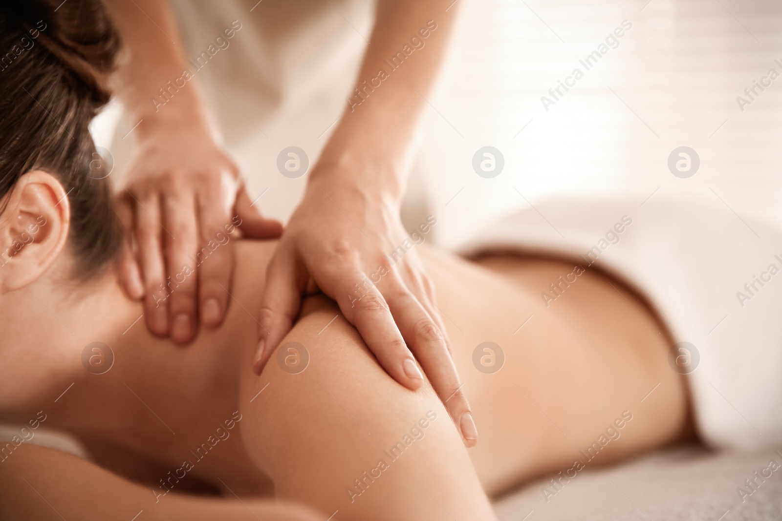 Photo of Young woman receiving shoulder massage in spa salon, closeup