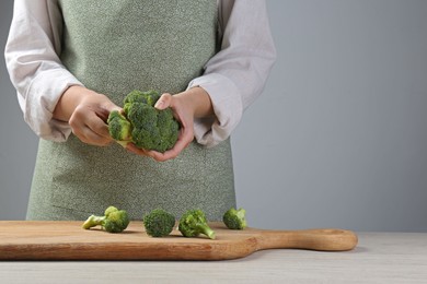 Photo of Woman separating fresh broccoli at wooden table, closeup. Space for text