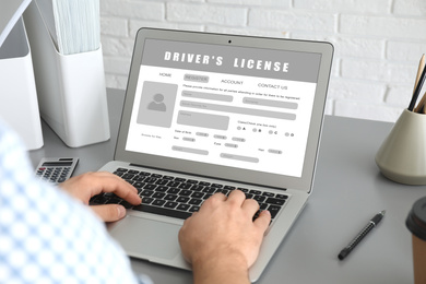 Image of Man filling in driver's license form online on website using laptop, closeup