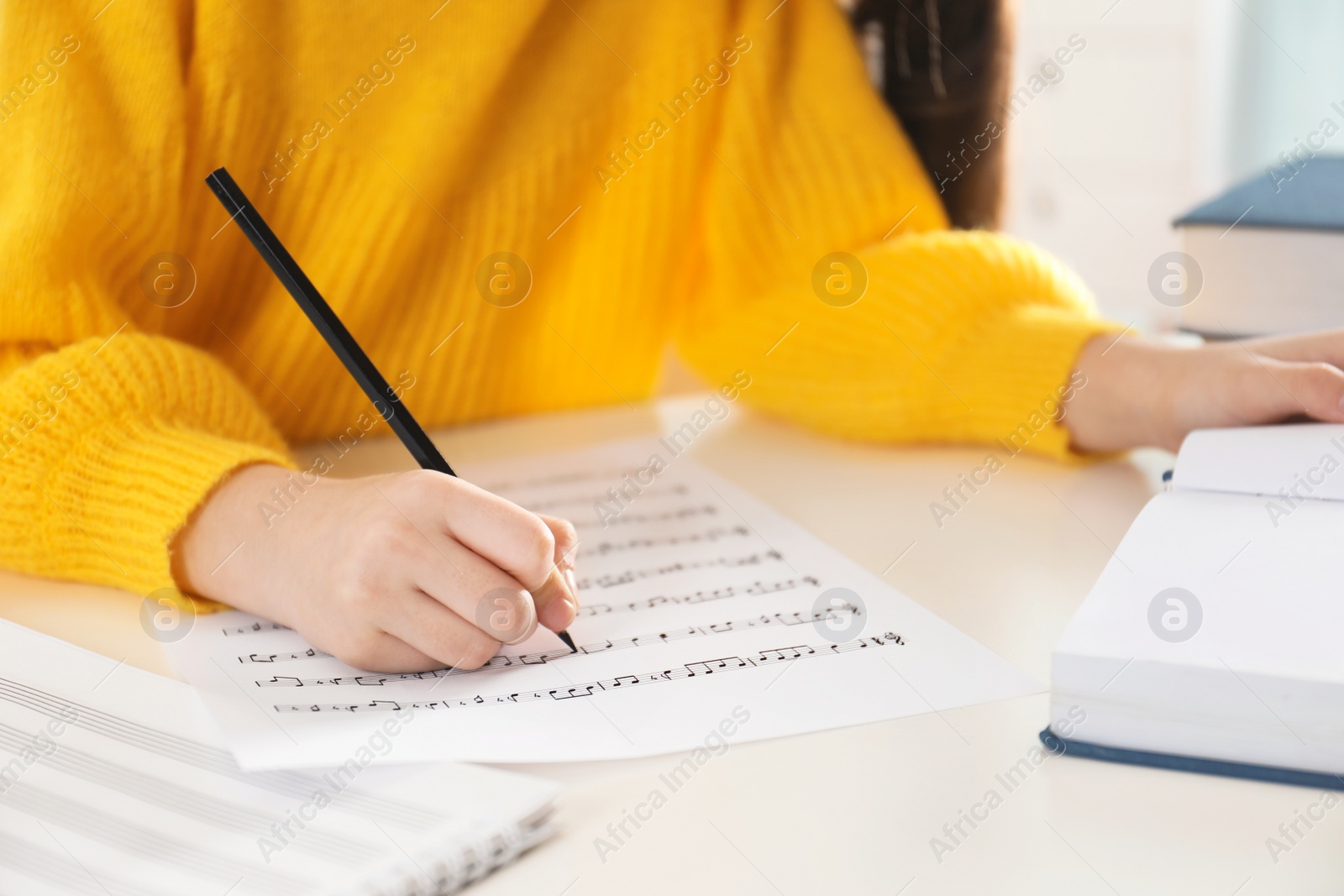 Photo of Child writing music notes at table, closeup