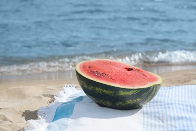 Half of fresh juicy watermelon on beach blanket near sea