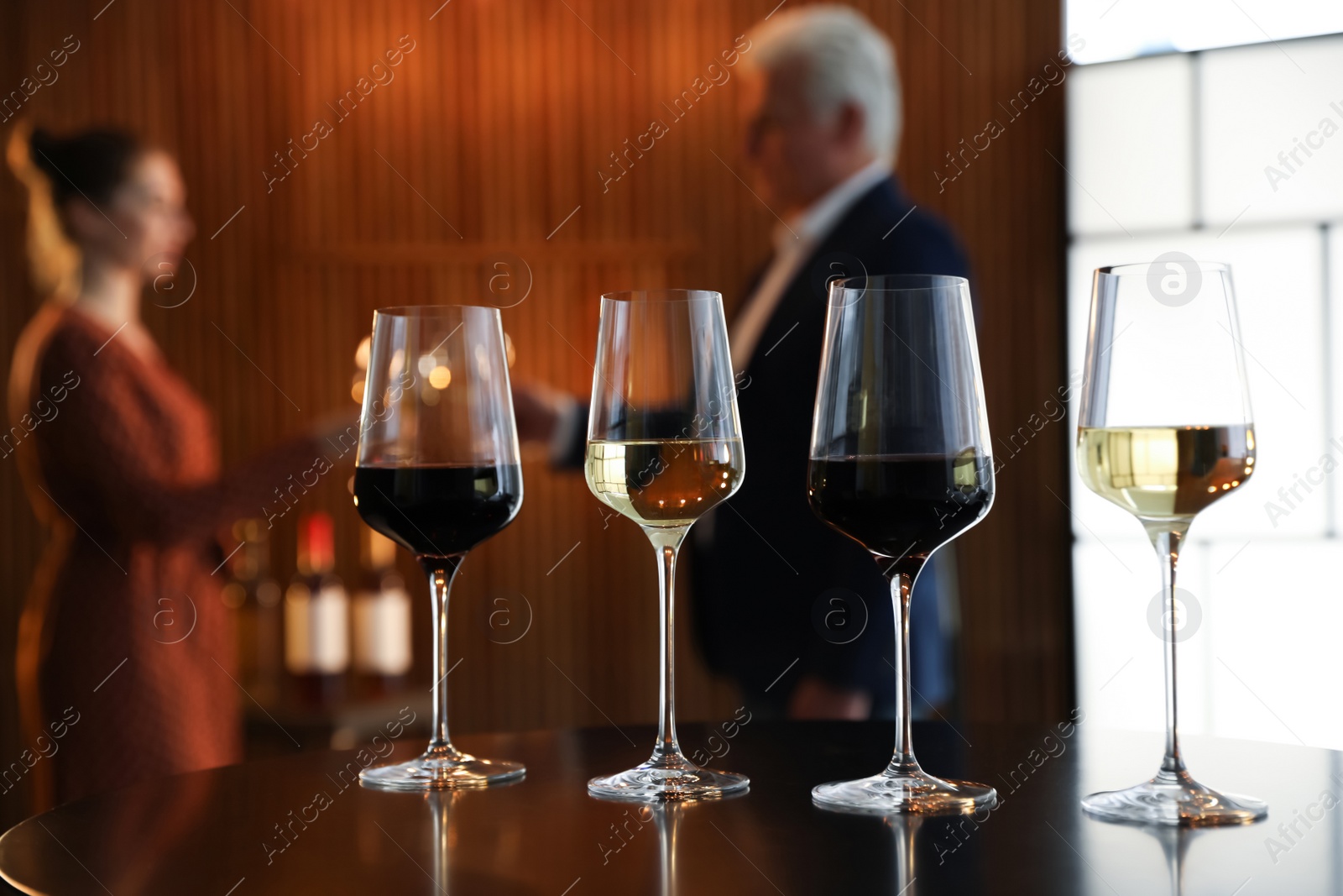 Photo of Glasses of different wines on table against blurred background