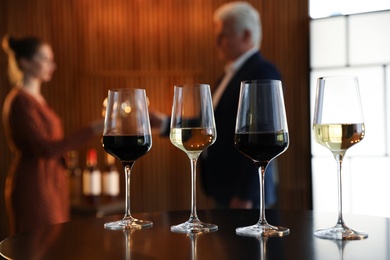 Photo of Glasses of different wines on table against blurred background