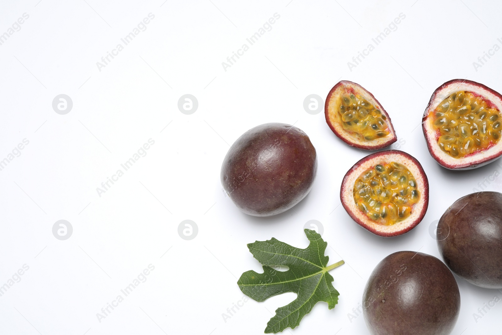 Photo of Fresh ripe passion fruits (maracuyas) with leaf on white background, flat lay. Space for text