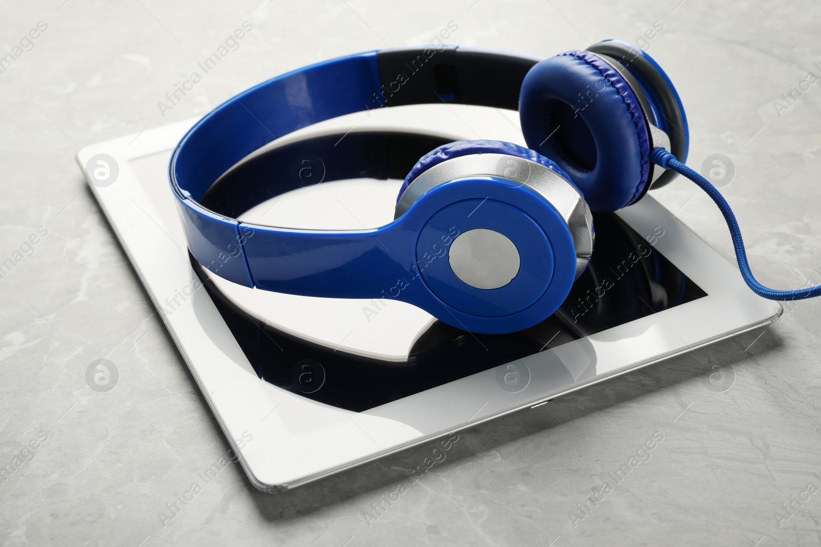 Photo of Modern headphones and tablet on light table