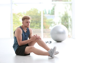 Photo of Man in sportswear suffering from knee pain at gym