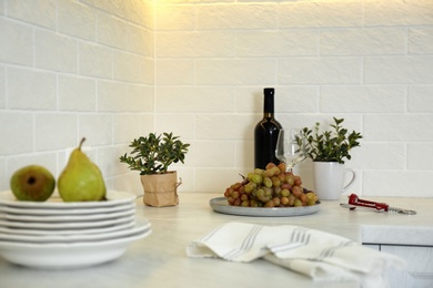 Red wine and fruits on white countertop in modern kitchen