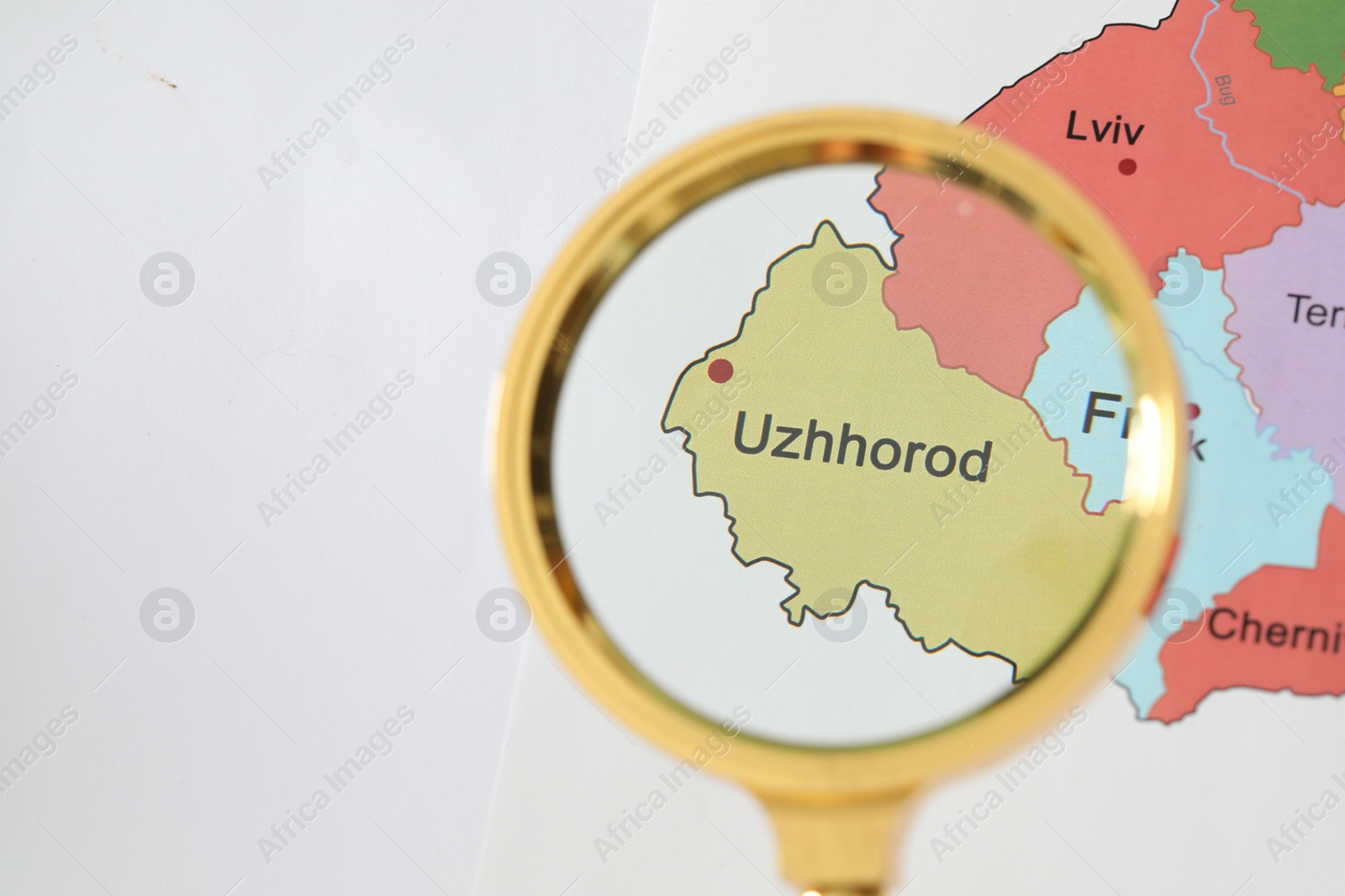 Photo of Golden magnifying glass above Uzhhorod region on map of Ukraine, closeup