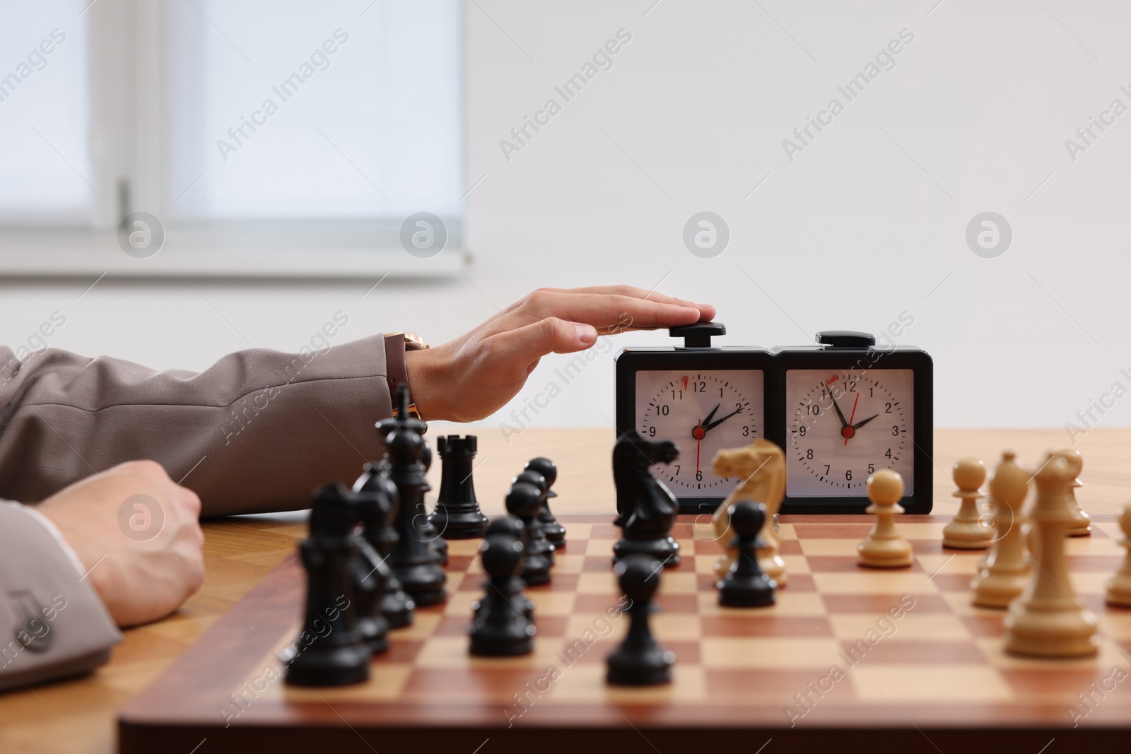 Photo of Man turning on chess clock during tournament at table, closeup