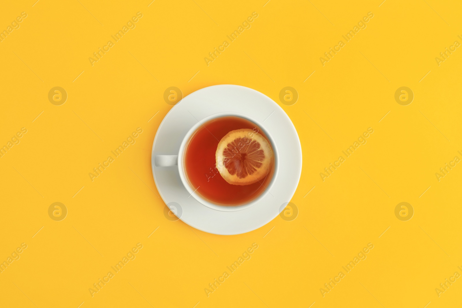 Photo of Cup of tea on yellow background, top view