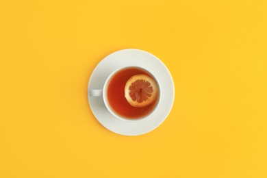 Photo of Cup of tea on yellow background, top view