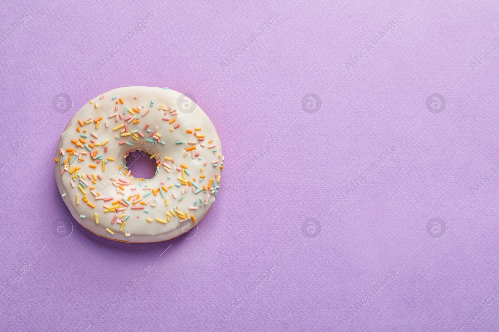 Photo of Delicious glazed doughnut with sprinkles on color background, top view