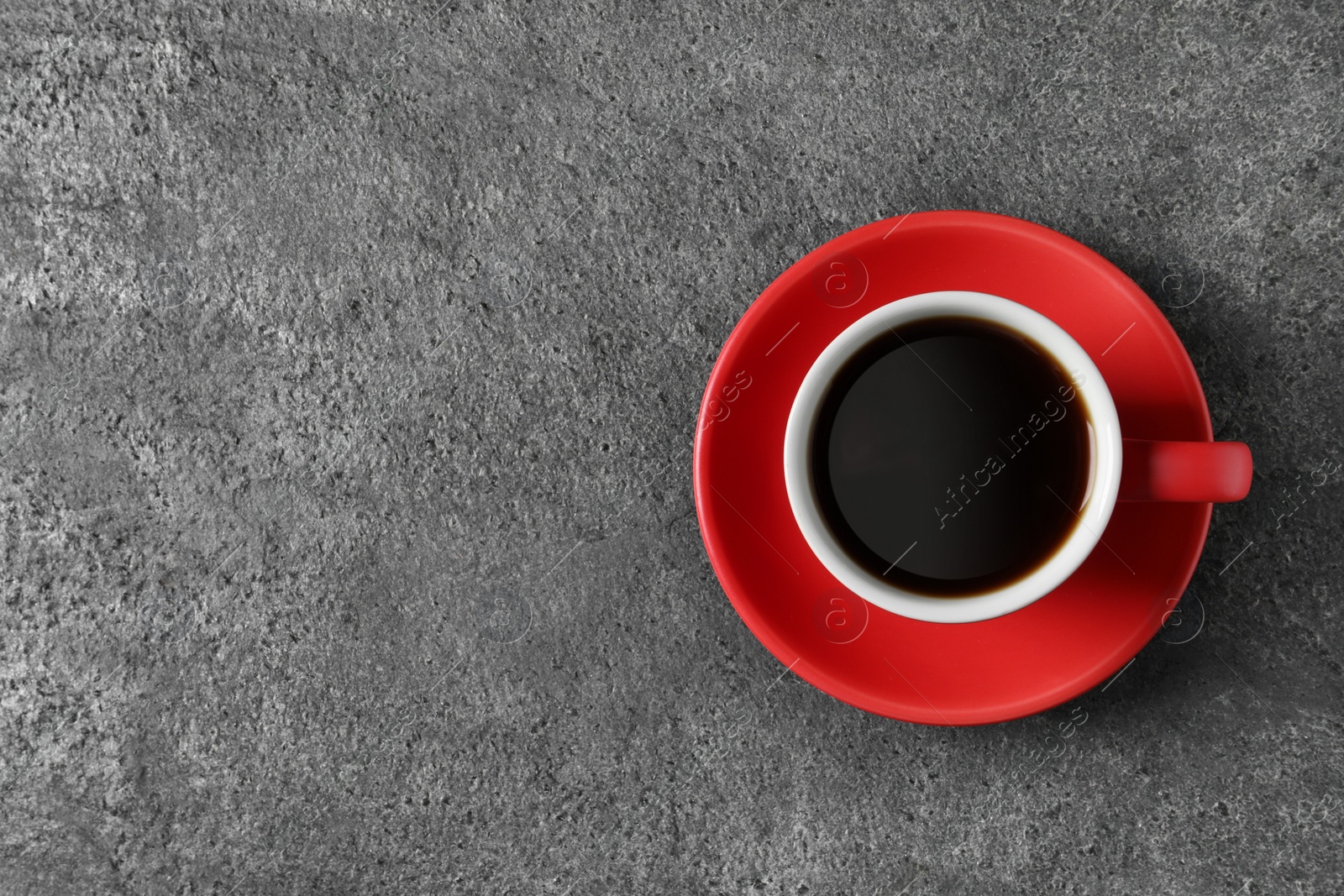 Photo of Cup with aromatic coffee on grey textured table, top view. Space for text