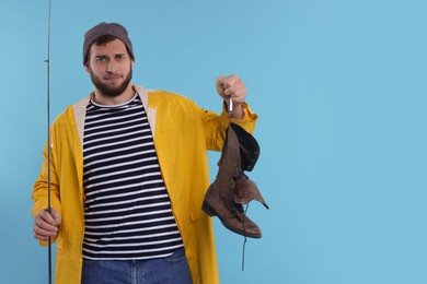 Photo of Fisherman with rod and old boot on light blue background, space for text