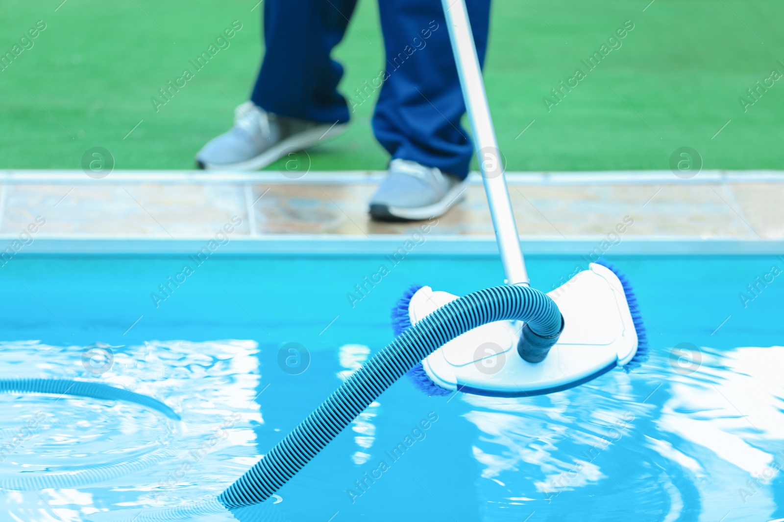 Photo of Male worker cleaning outdoor pool with underwater vacuum