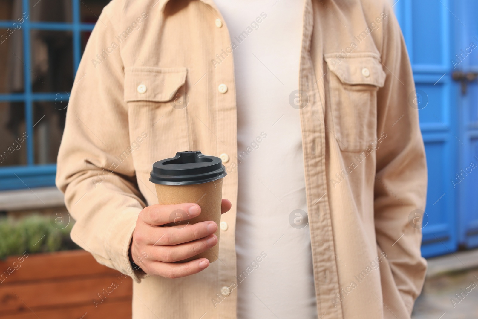 Photo of Coffee to go. Man with paper cup of drink outdoors, closeup