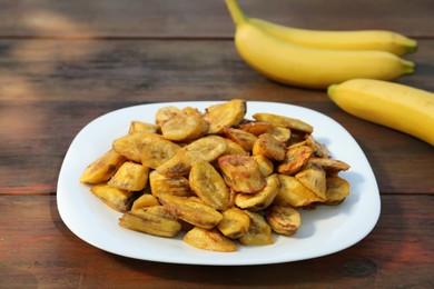 Photo of Tasty deep fried banana slices on wooden table