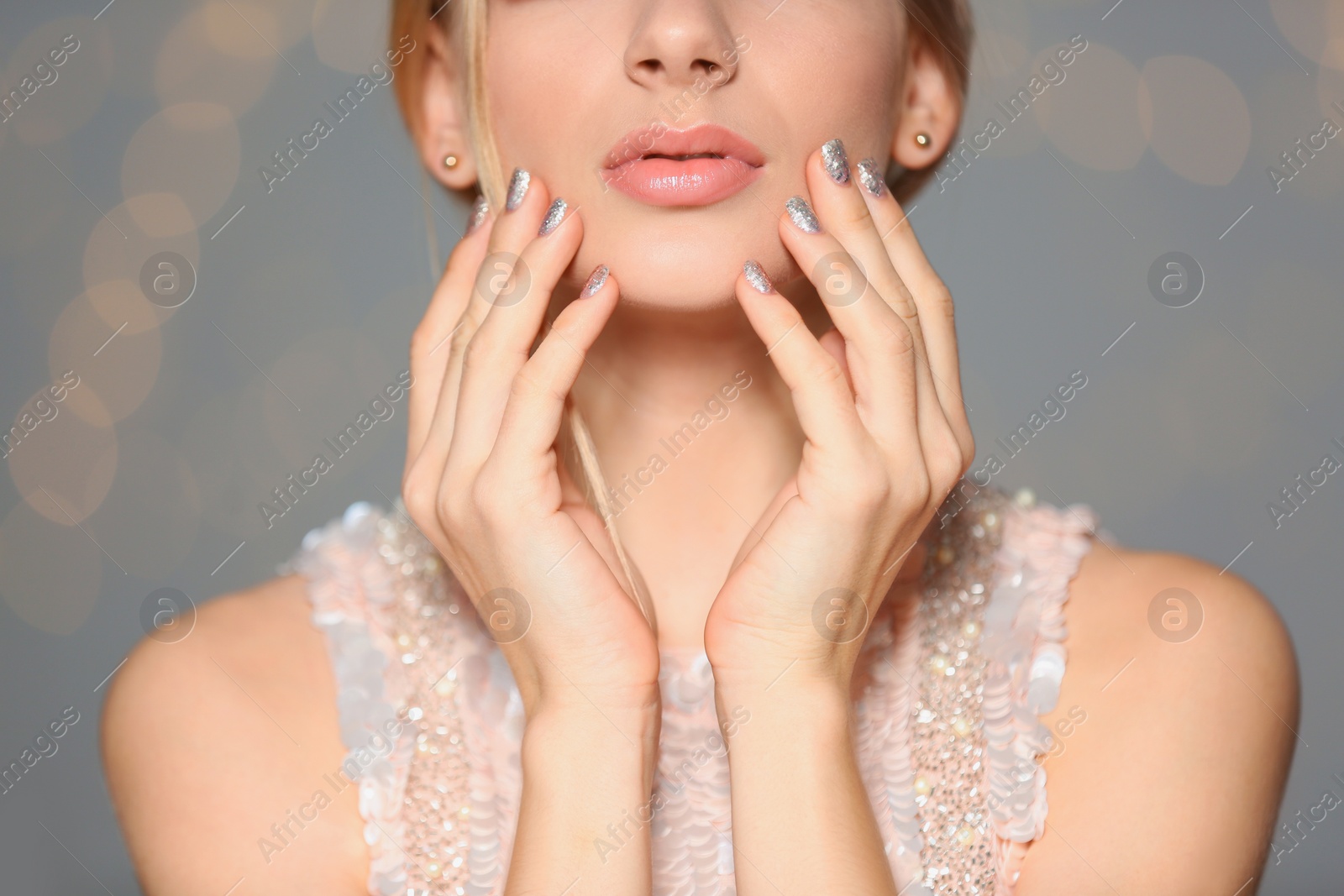Photo of Beautiful young woman with shiny manicure on blurred background, closeup. Nail polish trends