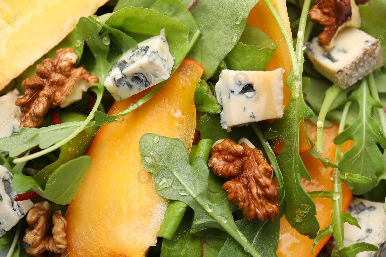 Photo of Tasty salad with persimmon, blue cheese and walnuts as background, above view