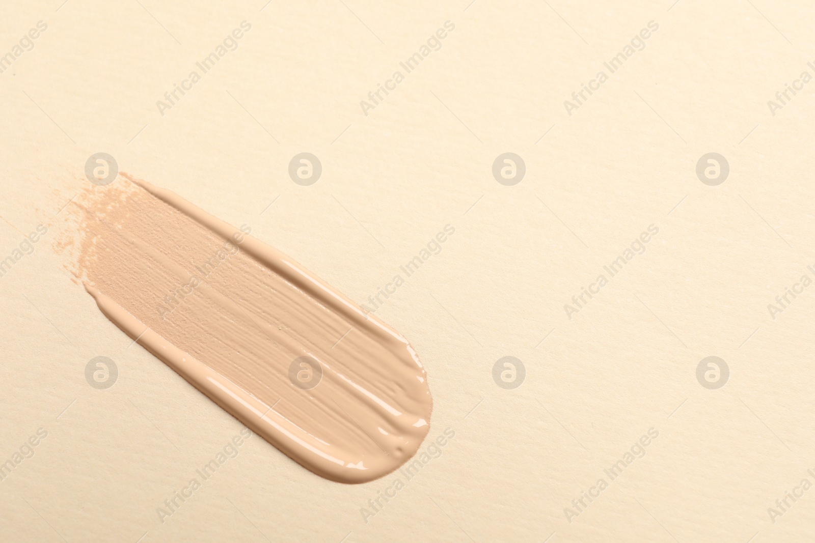 Photo of Smear of skin foundation on beige background, top view. Space for text