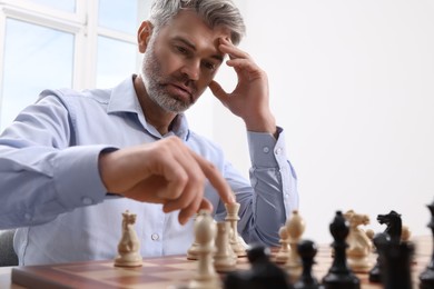 Photo of Man playing chess during tournament at chessboard indoors