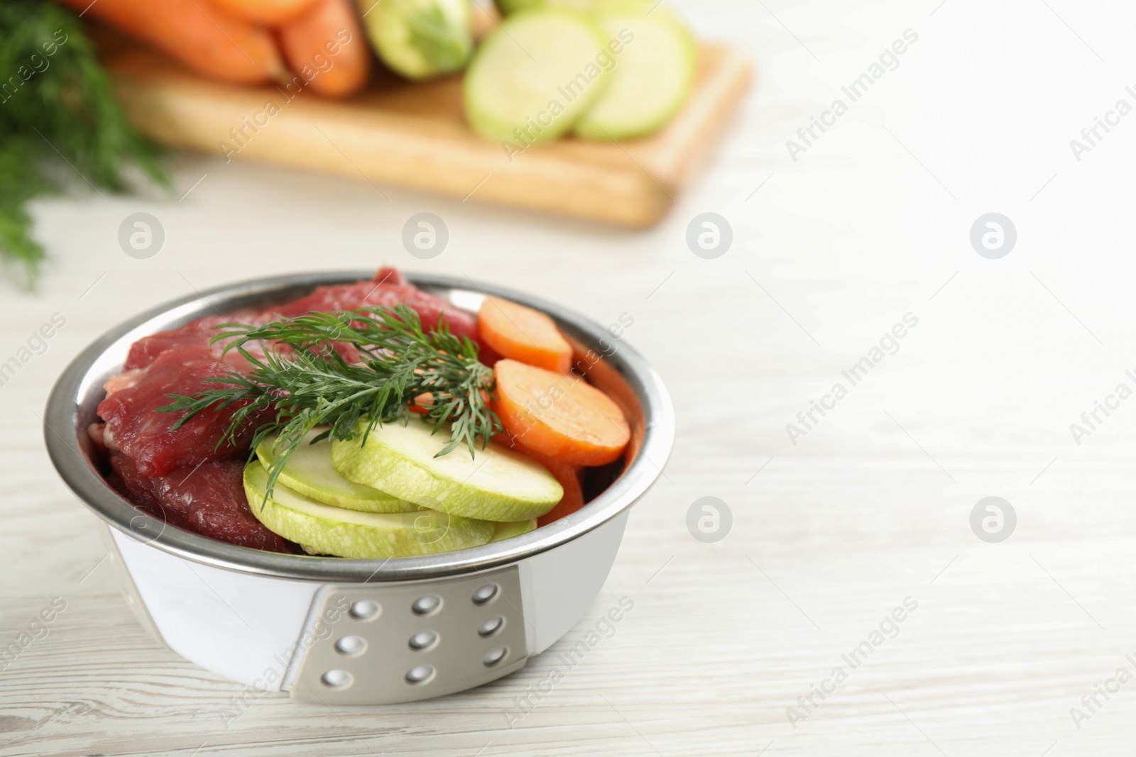 Photo of Natural pet food in feeding bowl on white wooden table, closeup. Space for text