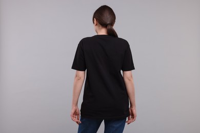 Woman in stylish black t-shirt light grey on background, back view