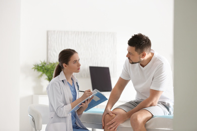 Photo of Female orthopedist examining patient with injured knee in clinic