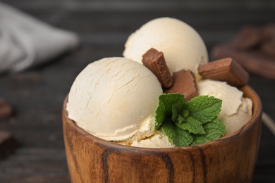 Photo of Delicious vanilla ice cream with chocolate and mint in bowl on table, closeup