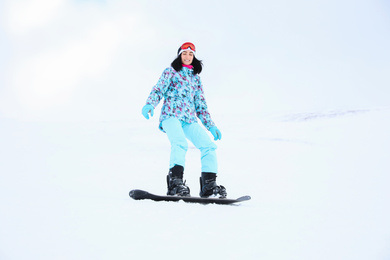 Young woman snowboarding on hill at mountain resort. Winter vacation