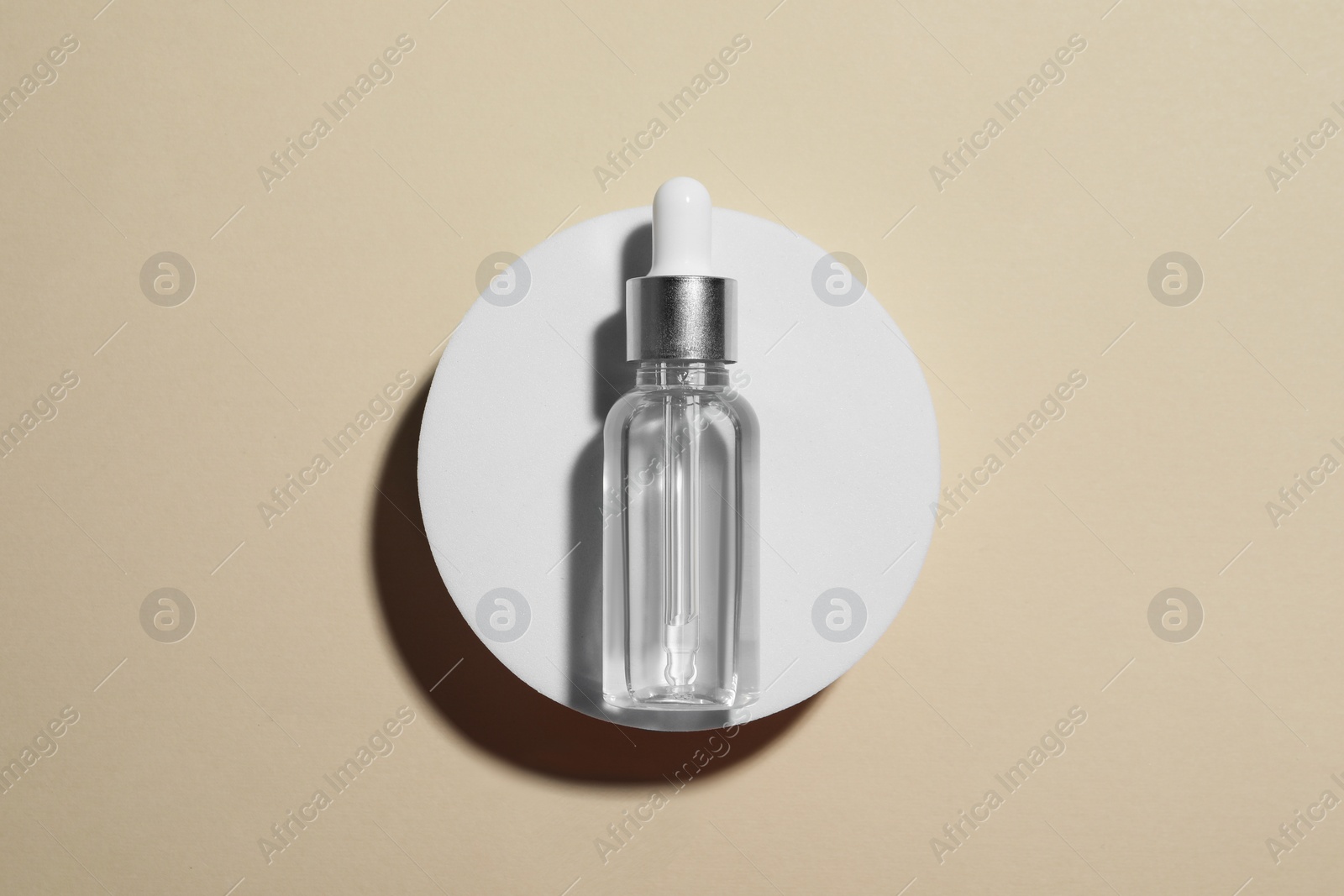 Photo of Bottle of cosmetic oil on beige background, top view