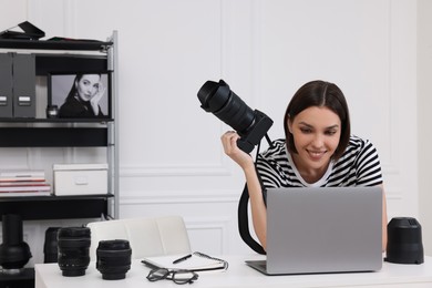 Photo of Young professional photographer with camera working on laptop in modern photo studio, space for text