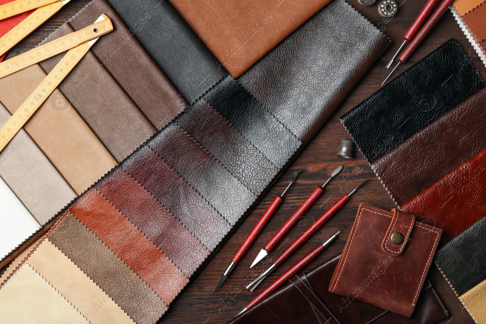 Photo of Flat lay composition with leather samples and tools on  wooden table