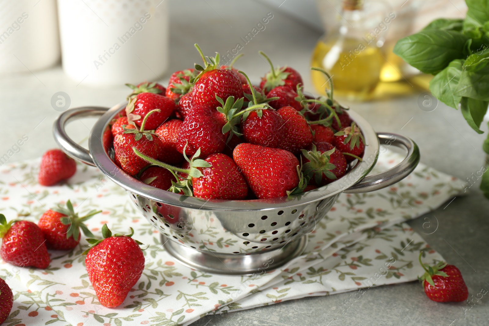 Photo of Metal colander with fresh strawberries on grey table