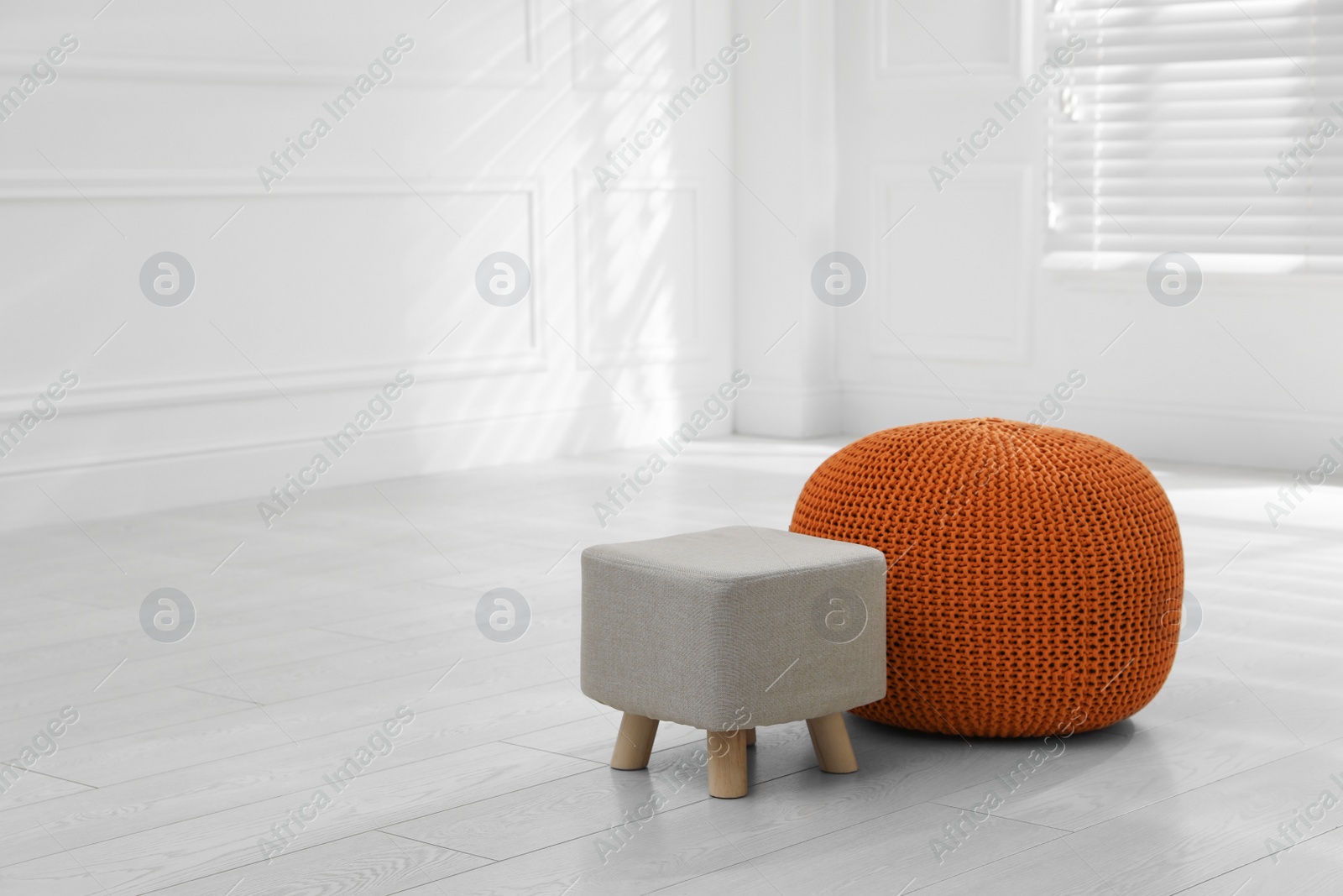 Photo of Stylish pouf and ottoman in room, space for text