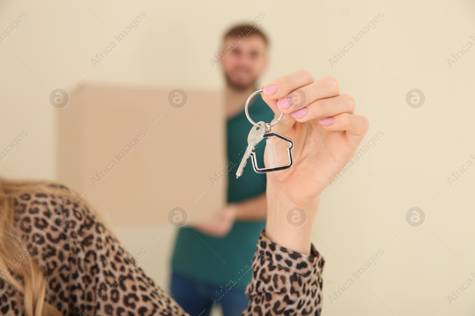 Photo of Woman with house key and her blurred boyfriend on background, closeup of hand