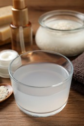 Photo of Homemade natural rice water and cosmetic products on wooden table, closeup