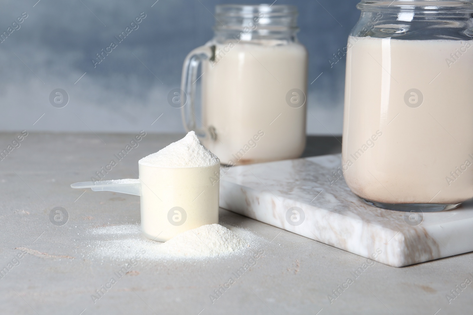 Photo of Scoop of protein powder and jar with shake on table