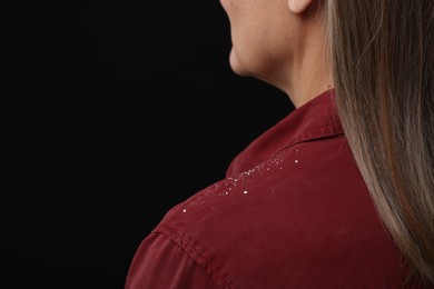 Photo of Woman with dandruff on her shirt against black background, closeup. Space for text